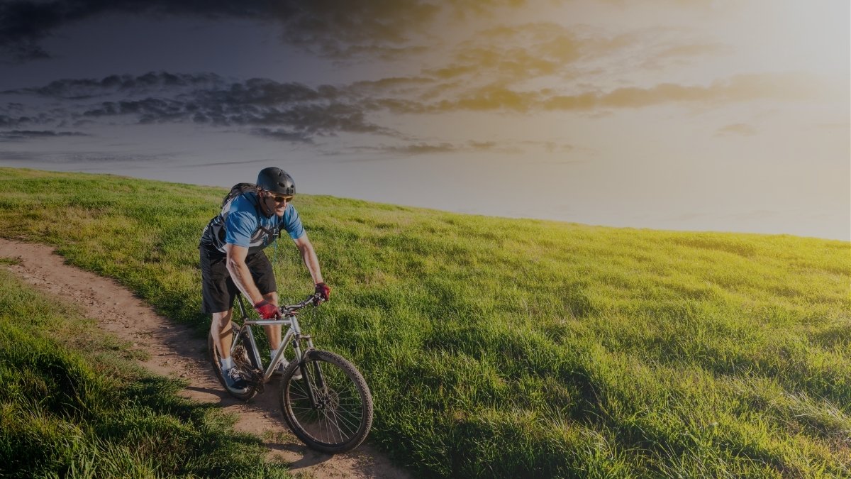 Ciclista adulto con casco recorriendo un sendero en un entorno natural