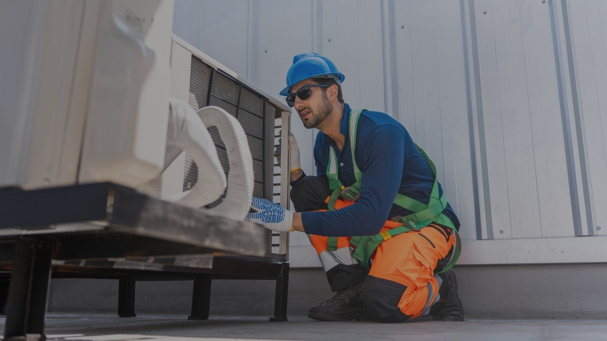 Técnico con equipo de protección realizando mantenimiento a un sistema de climatización