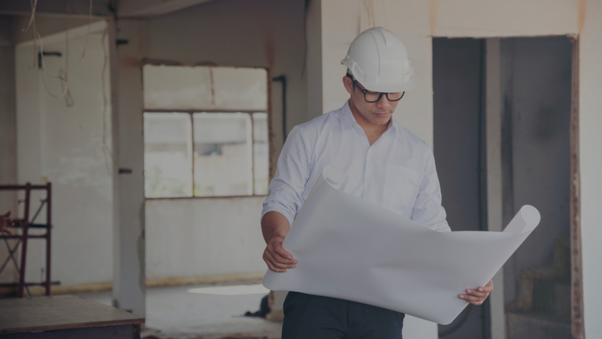 Profesional con casco revisando planos dentro de una obra en construcción