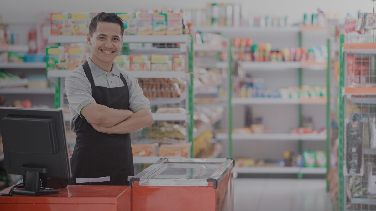 Comerciante frente al mostrador de un pequeño negocio durante una jornada normal de trabajo