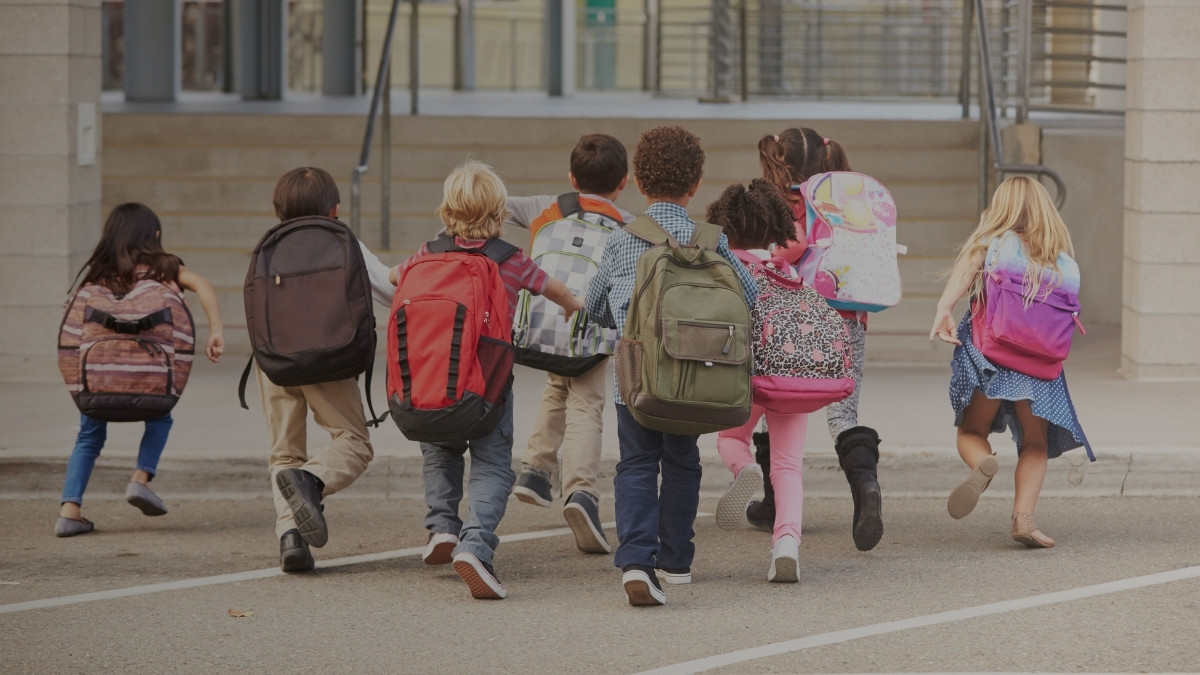 Grupo de estudiantes con mochilas caminando hacia un centro educativo